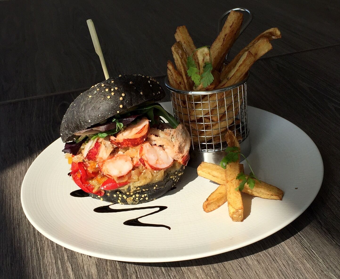 A plate with a sandwich, fries, and a decorative sauce line.