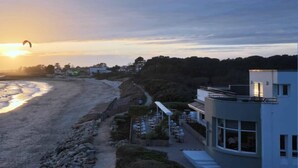 A coastal building with a beach view, a paved path, and outdoor seating. - Logis Hôtel & Restaurant Les Mouettes - Larmor Plage, proche de Lorient (Larmor-Plage)