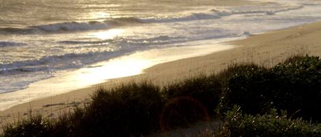 A beach with waves and sunlight reflecting on the water.