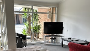 A hotel room with a bed, a TV, a desk, and a red chair. - Middle Park Motel (Blenheim)
