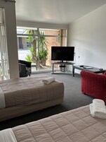 Una habitación de hotel con una cama, televisor, escritorio y una silla roja.