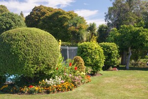Un jardín bien cuidado con diversas plantas florecientes y setos ordenados.
