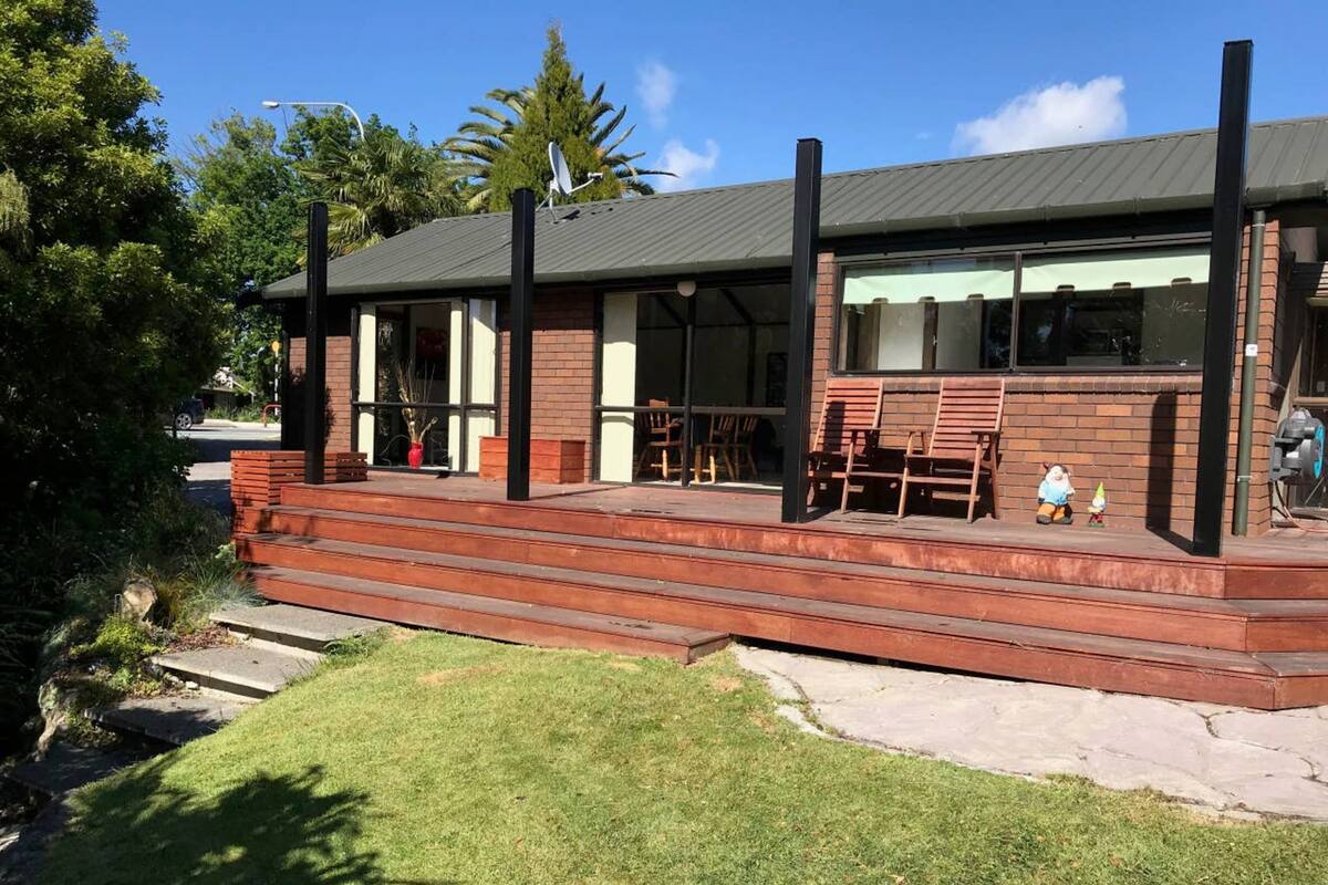 A modern building with a brick exterior, a flat roof, and a covered outdoor seating area with wooden chairs.
