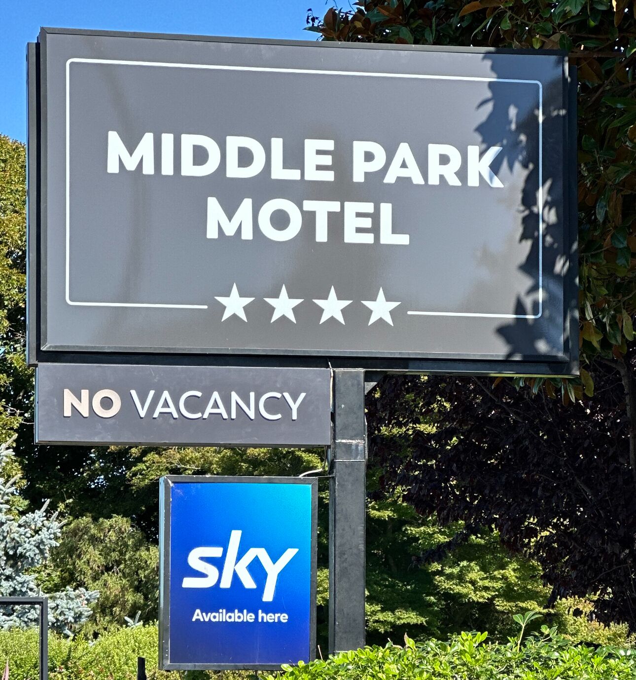 Schild des Middle Park Motel mit 'Keine freien Zimmer'-Hinweis und Schild zur Wettervorhersage.