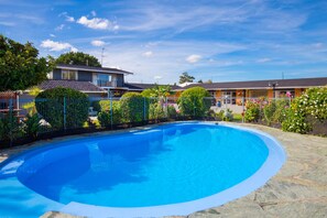 Una piscina rodeada de una valla, con un edificio al fondo.