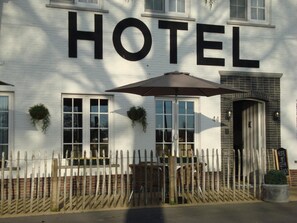 A hotel with a prominent 'HOTEL' sign, a wooden fence, and a potted plant. - Hotel Amaryllis (Maldegem)