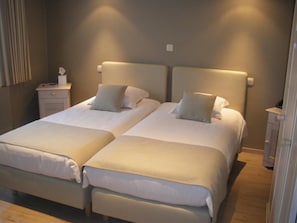 A double bed with a headboard, a bedside table, and a nightstand. - Hotel Amaryllis (Maldegem)