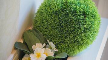 Un rincón con una esfera verde parecida a musgo, flores blancas y hojas verdes.