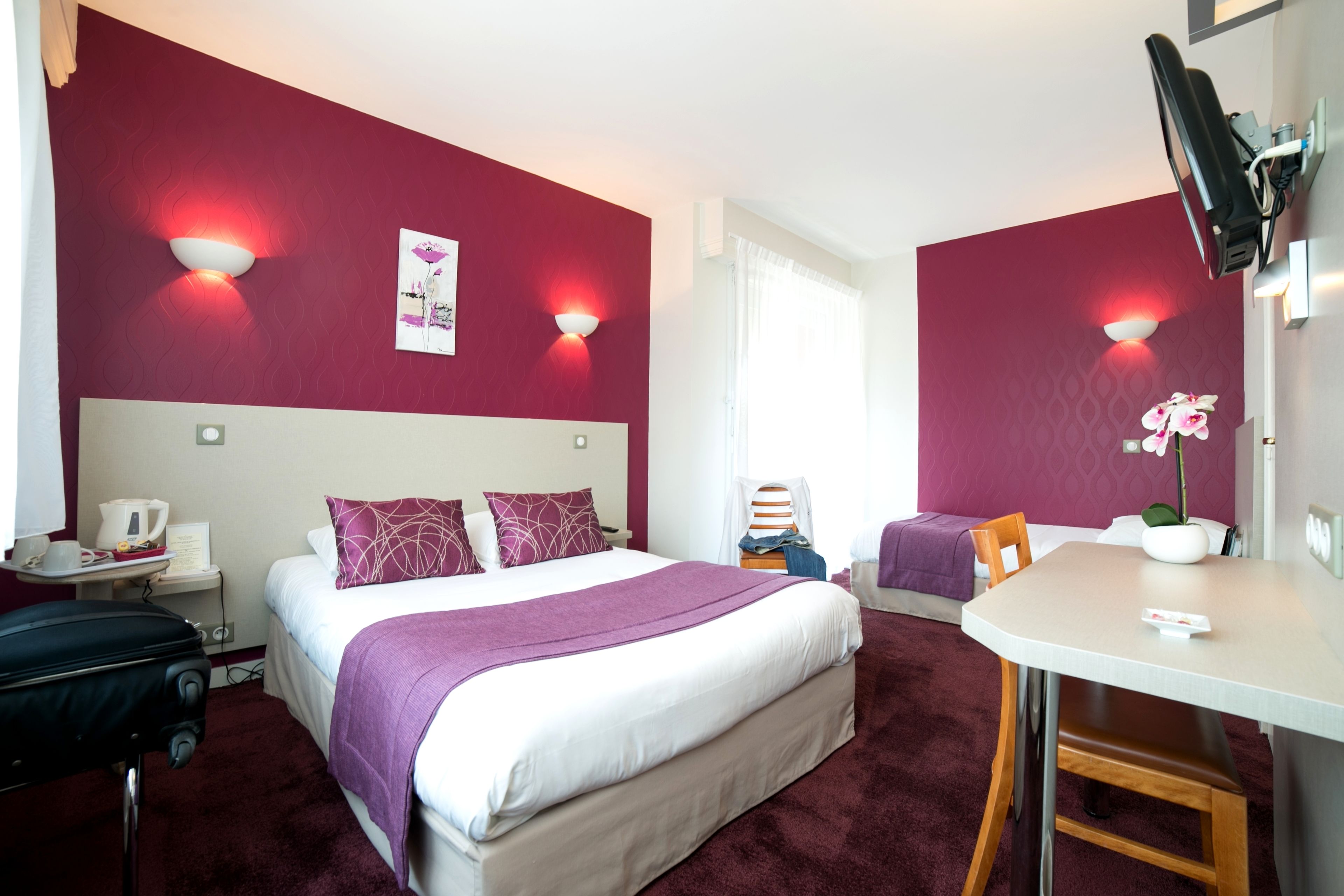Ein Hotelzimmer mit einem großen Bett, einem Schreibtisch, einem Stuhl und einem kleinen Tisch.