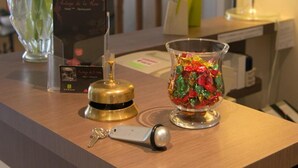Ein Hotelrezeptionstresen mit Blumen in einer Vase, einer Lampe, einem Schlüsselanhänger und einem dekorativen Glasbehälter.