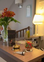 Un mostrador de recepción de hotel con un jarrón de flores, una lámpara, un llavero y un recipiente de vidrio decorativo.