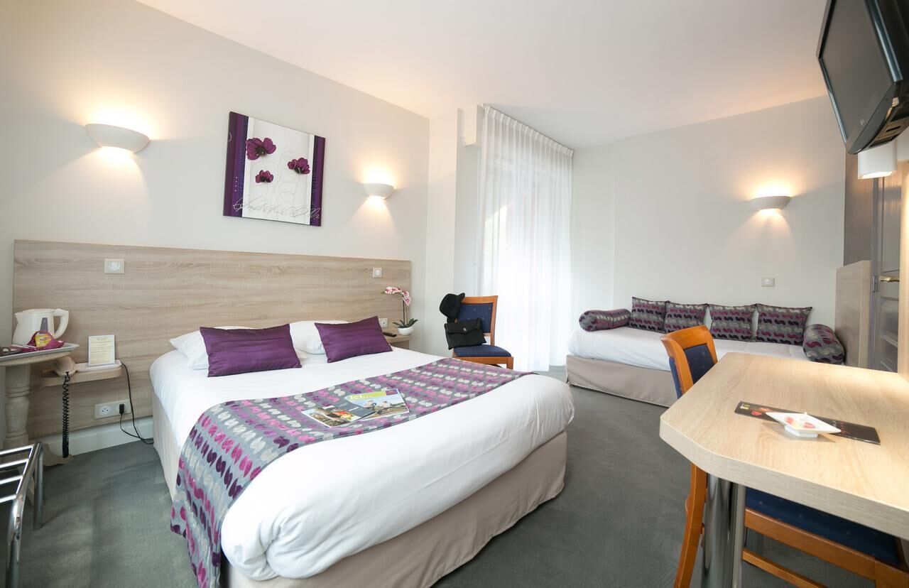 Une chambre d’hôtel comprenant un lit, une table de chevet, une chaise, un bureau et un téléviseur.