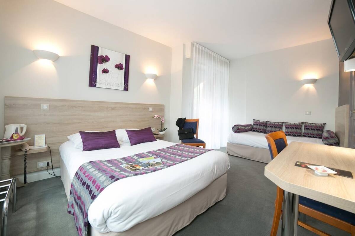 Ein Hotelzimmer mit Bett, Nachttisch, Stuhl, Schreibtisch und Fernseher.