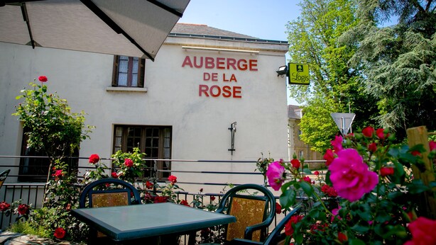 Ein Sitzbereich im Freien mit Tischen und Stühlen, umgeben von blühenden Rosen.