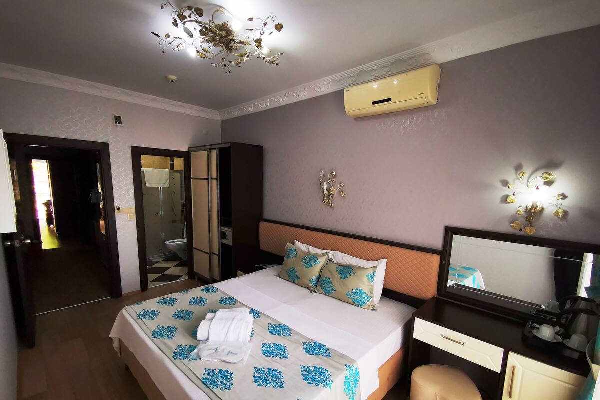 A hotel room with a bed, bedside table, desk, and a mirror.