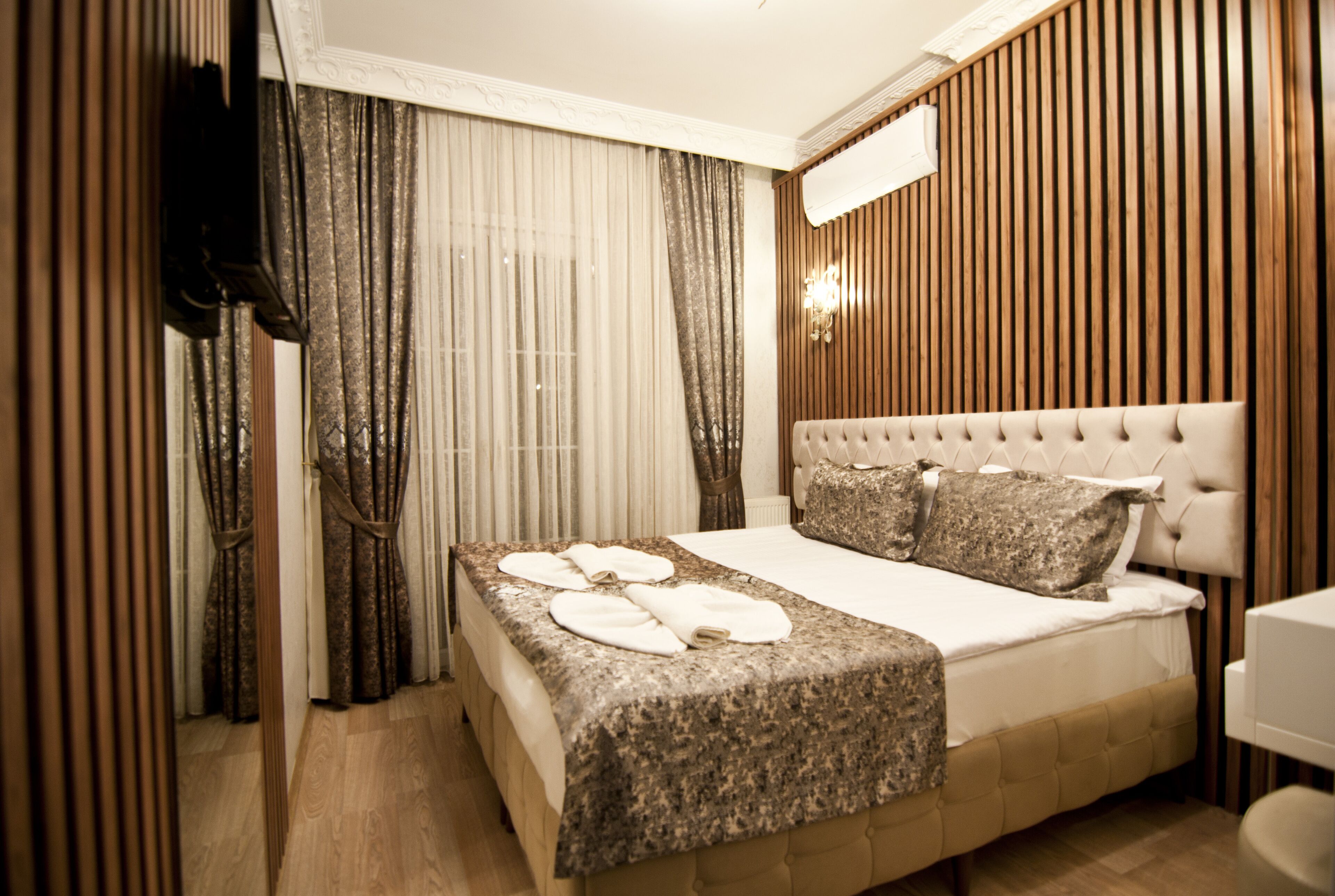 A hotel room with a large bed, a wooden headboard, and a television mounted on the wall.