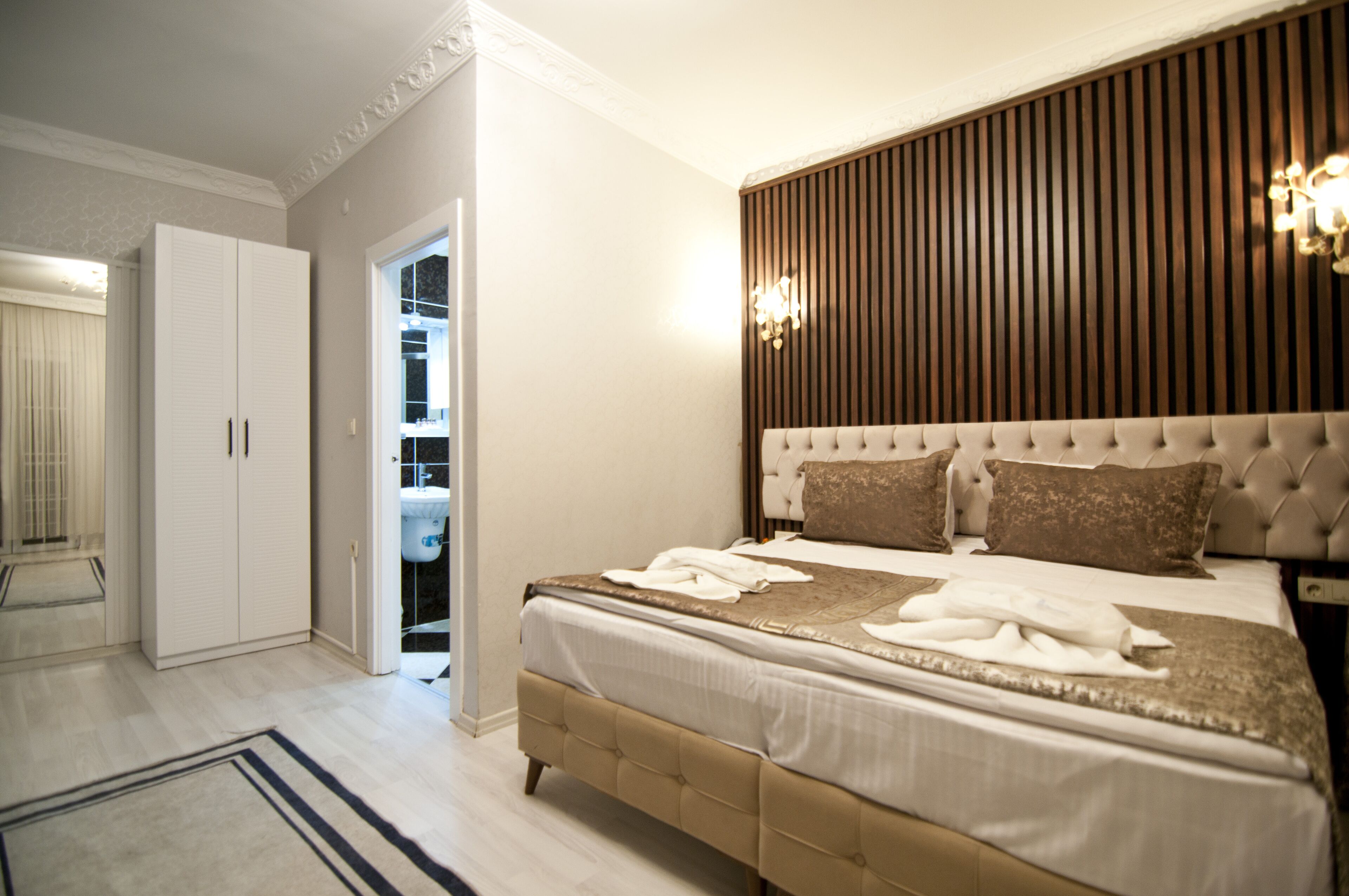A bedroom with a large bed, a wardrobe, and a bathroom visible through an open door.