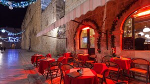 Zona de menjador a l'aire lliure amb taules i cadires, un edifici de pedra i decoracions festives.