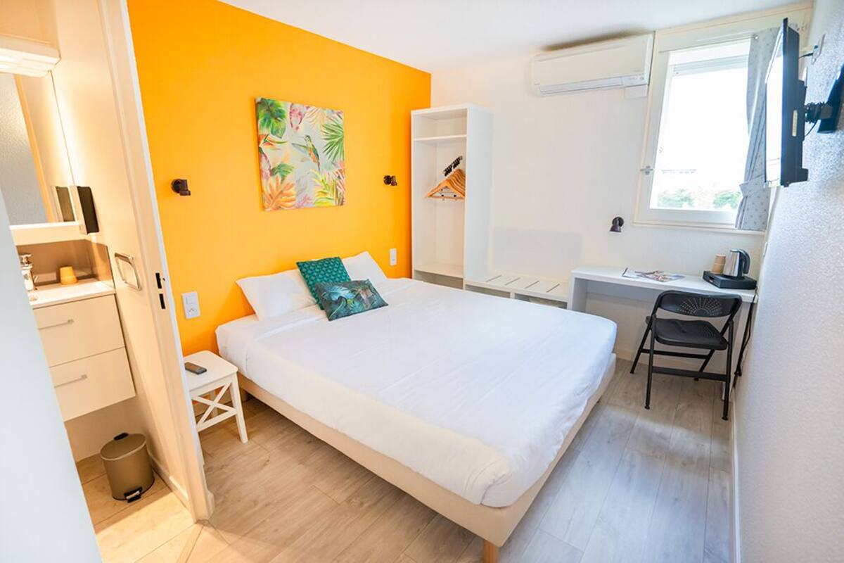 Un dormitorio con cama, escritorio y armario.