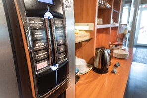 Eine Kaffeemaschine mit verschiedenen Getränkeauswahlen und integriertem Milchaufschäumer.