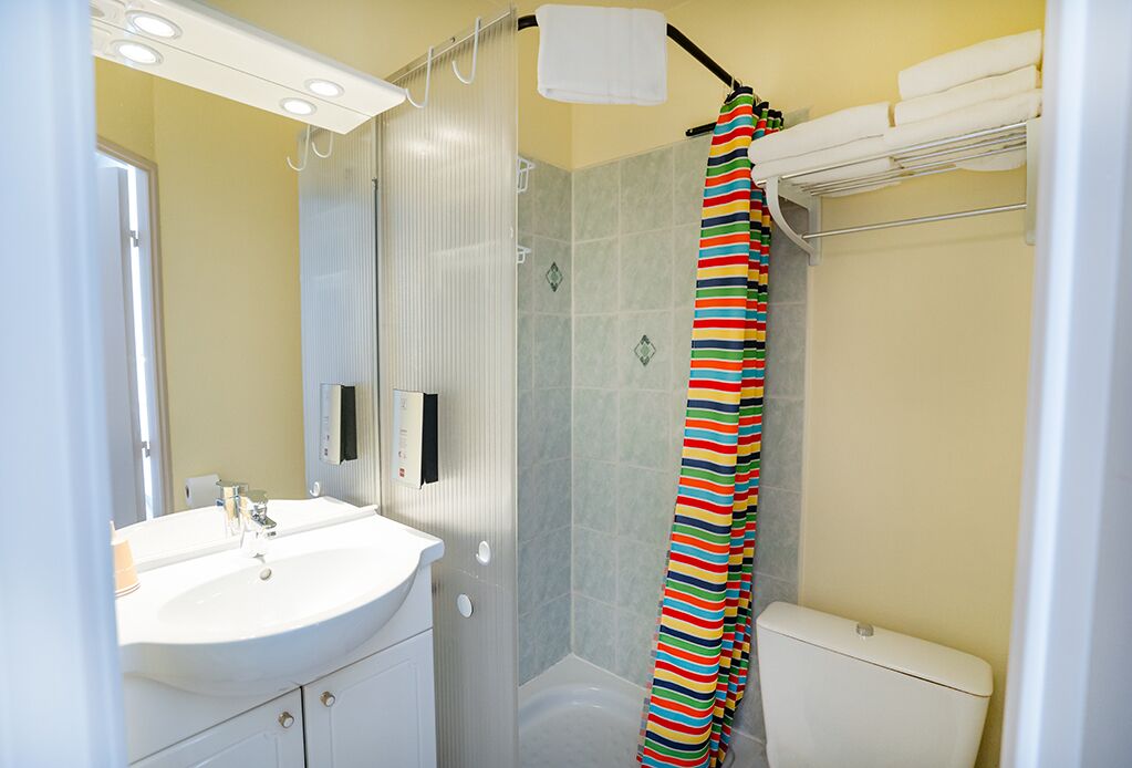 A bathroom with a white sink, a shower curtain, and a toilet.
