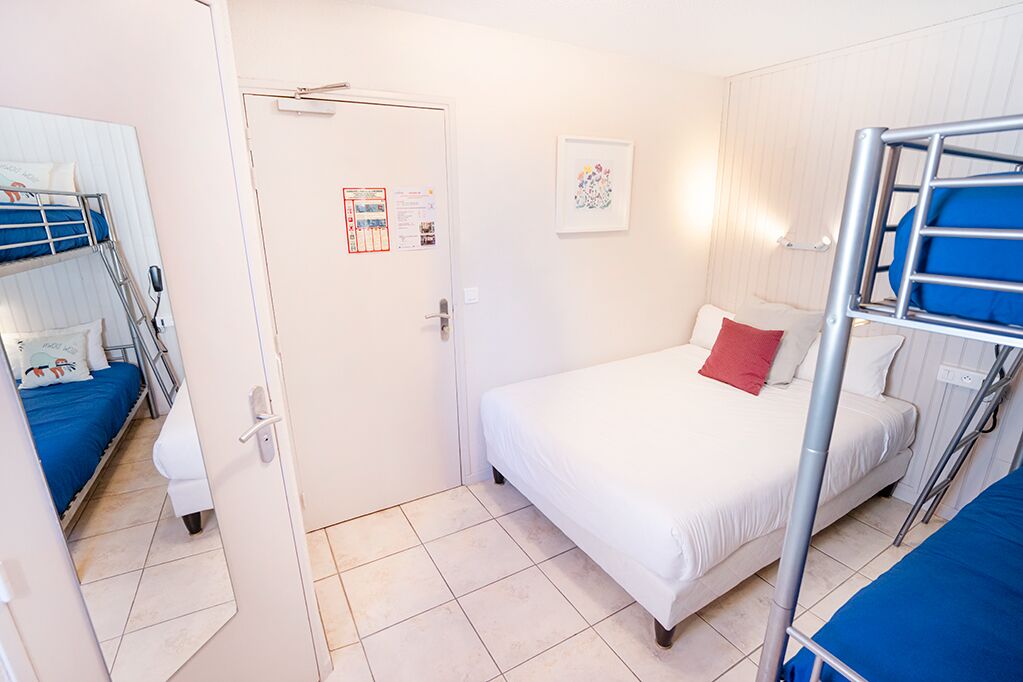 A room with bunk beds, a door with a calendar, and a framed picture on the wall.