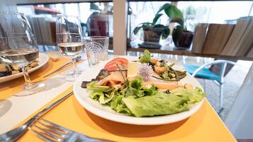 Ein Tisch mit Salat, Weingläsern und Besteck.