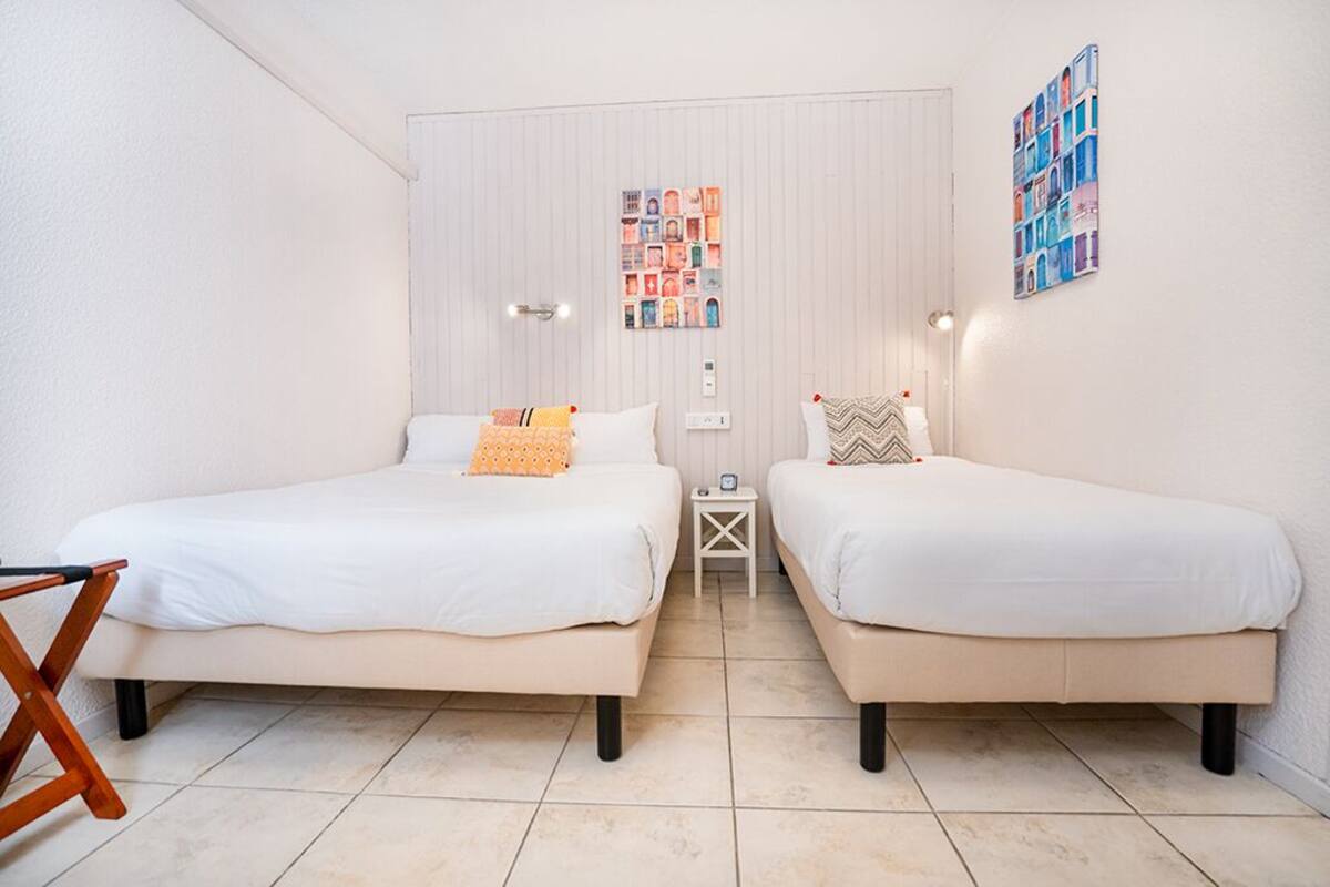 Un dormitorio con dos camas, una mesita y una silla.