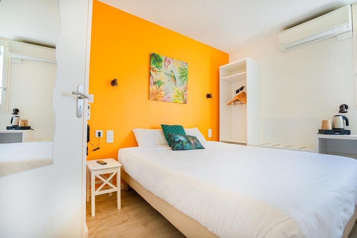 A bedroom with a bed, a small bedside table, a wall-mounted shelf, and a painting.