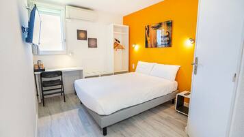 A bedroom with a bed, a desk, a chair, a wardrobe, and a painting on the wall.