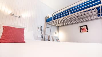 A bunk bed room with a ladder, a red pillow, a white wall, and a small bear picture.