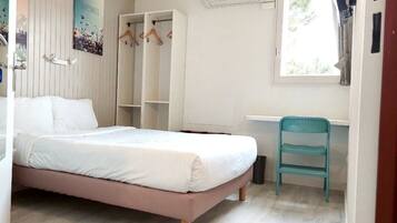 Un dormitorio con cama, escritorio, silla, armario y aire acondicionado.