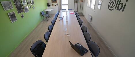 A conference room with a long table, chairs, and a projector screen.