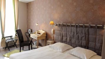 Habitación de hotel con cama, escritorio, silla, teléfono y lámpara.