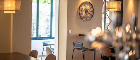 A modern dining area with a table and chairs, a wall clock, and pendant lighting.