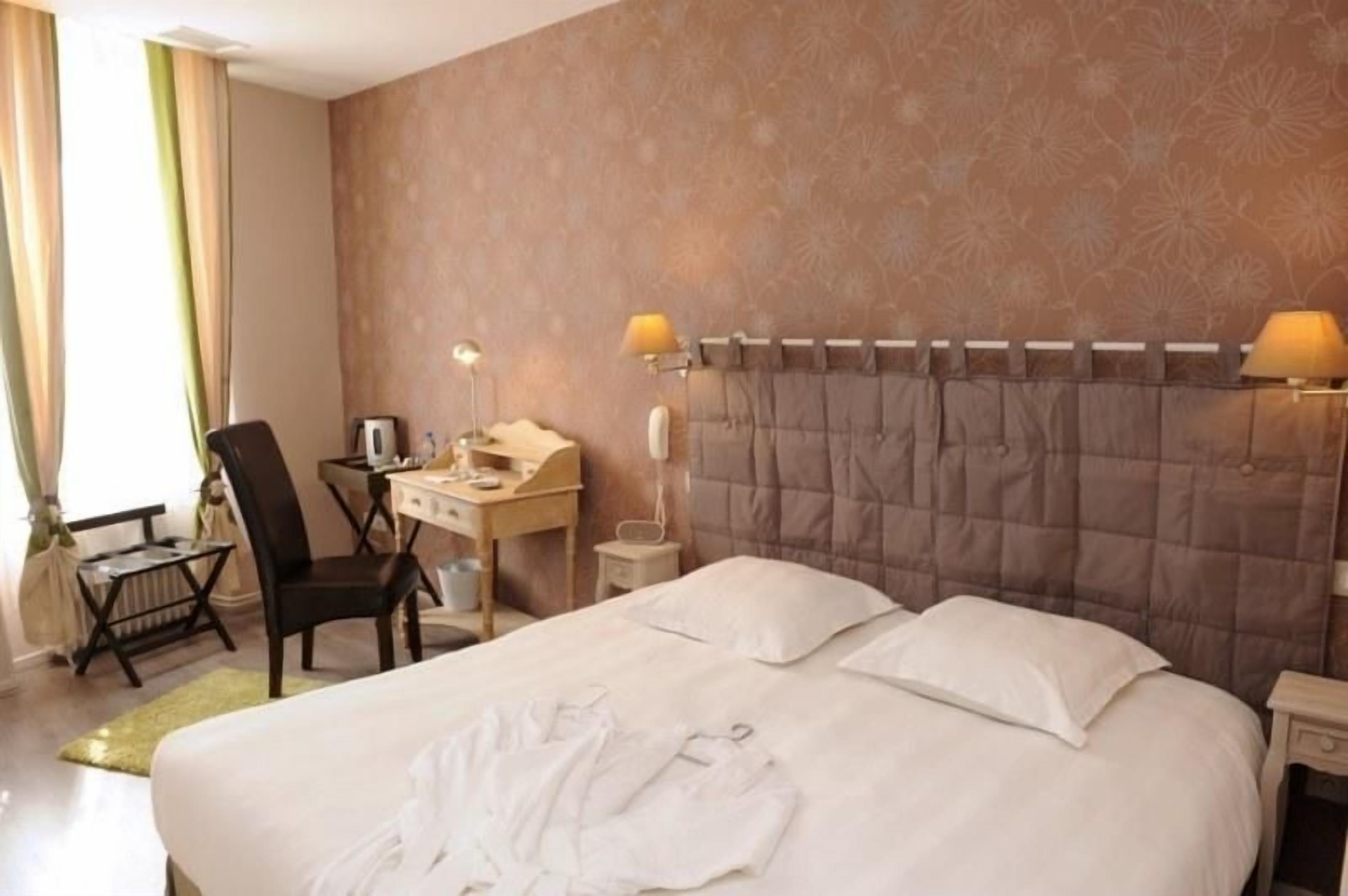 Una habitación de hotel con una cama, un escritorio, una silla, una lámpara y un teléfono.