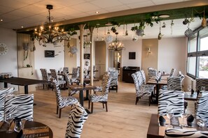 A restaurant with zebra-striped chairs, hanging plants, and chandeliers.
