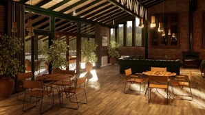 A spacious indoor area with wooden flooring, multiple tables and chairs, large potted plants, and a brick wall. - Valle Andino  (Uspallata)