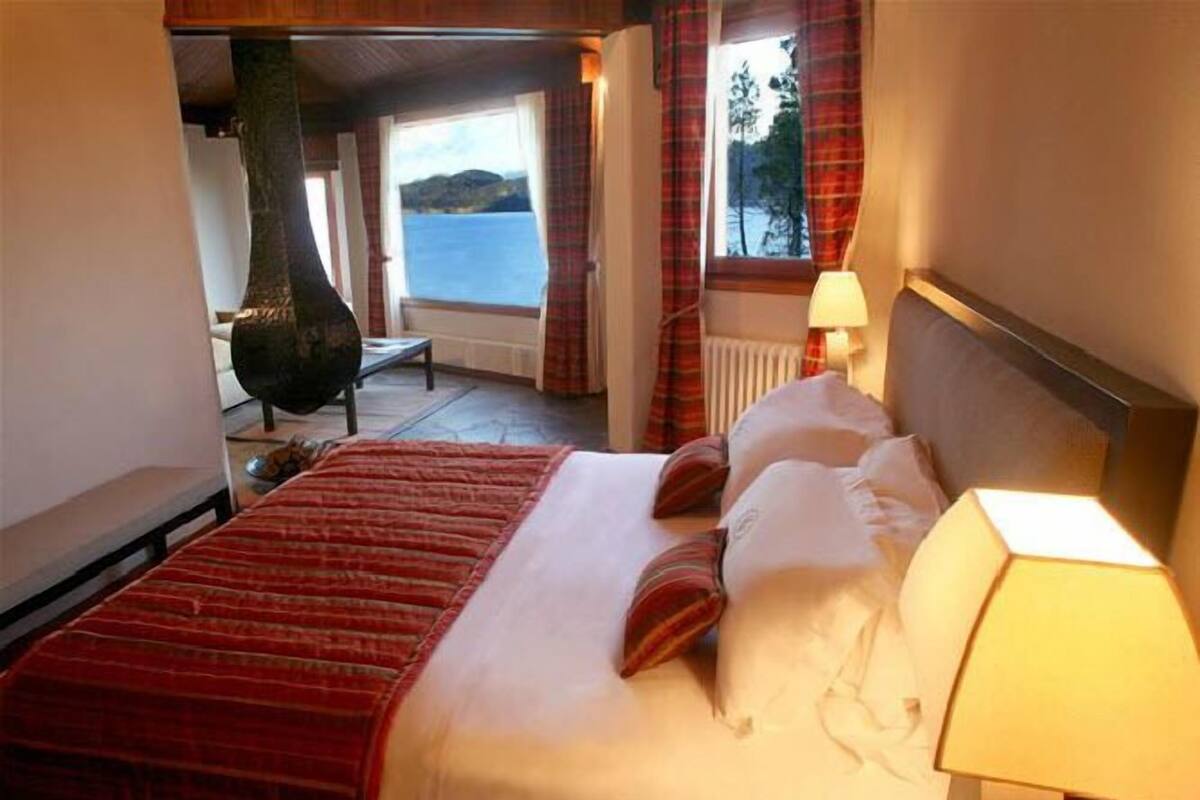 A hotel room with a bed, a lamp, and a view of the sea.
