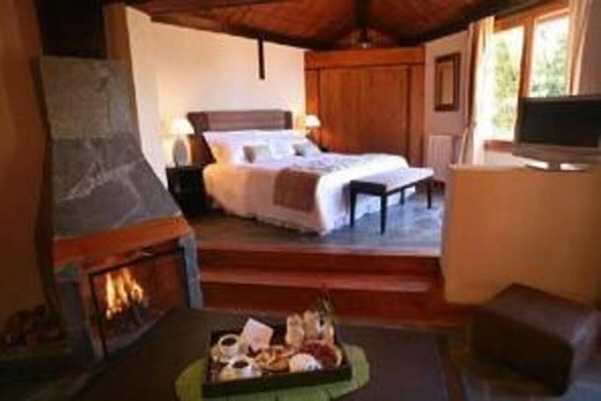 A cozy room with a fireplace, a bed, a TV, and a dining area with a tray of food.