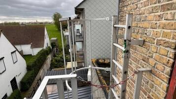 A residential building with a brick exterior, a metal staircase, and a view of a neighboring house.