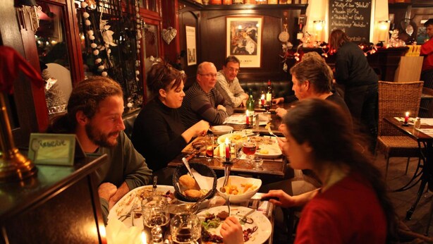 A group of people dining at a restaurant with wooden furniture and a cozy atmosphere. - The Piper's Pub (Middelkerke)