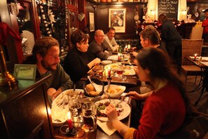 A group of people dining at a restaurant with wooden furniture and a cozy atmosphere. - The Piper's Pub (Middelkerke)