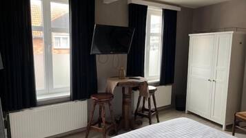 A bedroom with a bed, a desk, a chair, a wardrobe, and a television.