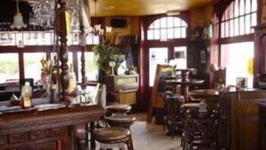 A bar with wooden furniture and a brick wall. - The Piper's Pub (Middelkerke)