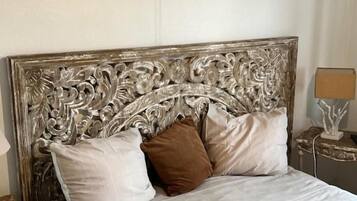 A bed with a decorative headboard, two pillows, and a bedside table with a lamp.