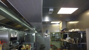 A commercial kitchen with stainless steel appliances, a ventilation system, and various cooking utensils and ingredients. - The Piper's Pub (Middelkerke)