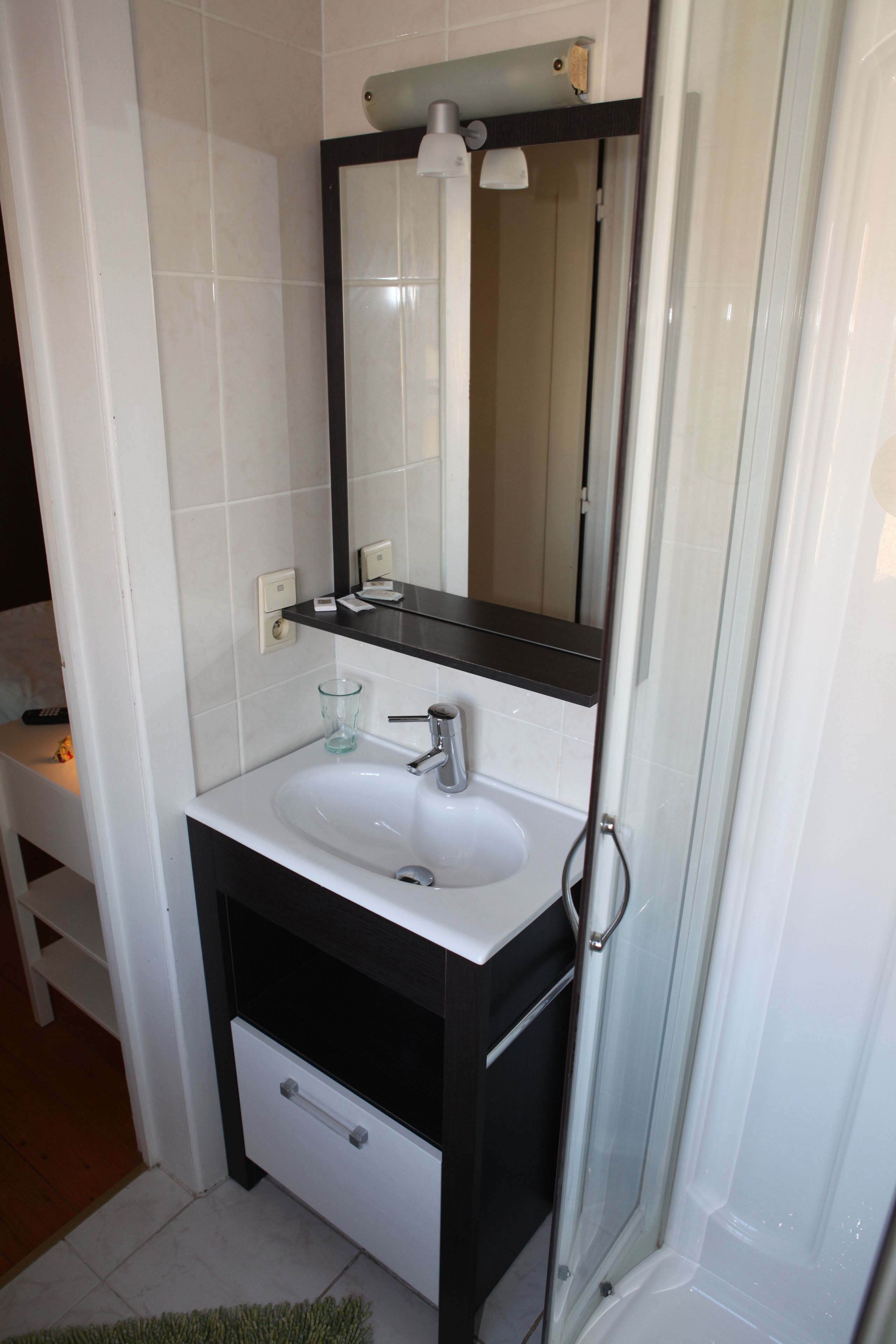 A bathroom with a white sink, black cabinet, and a glass shower enclosure.