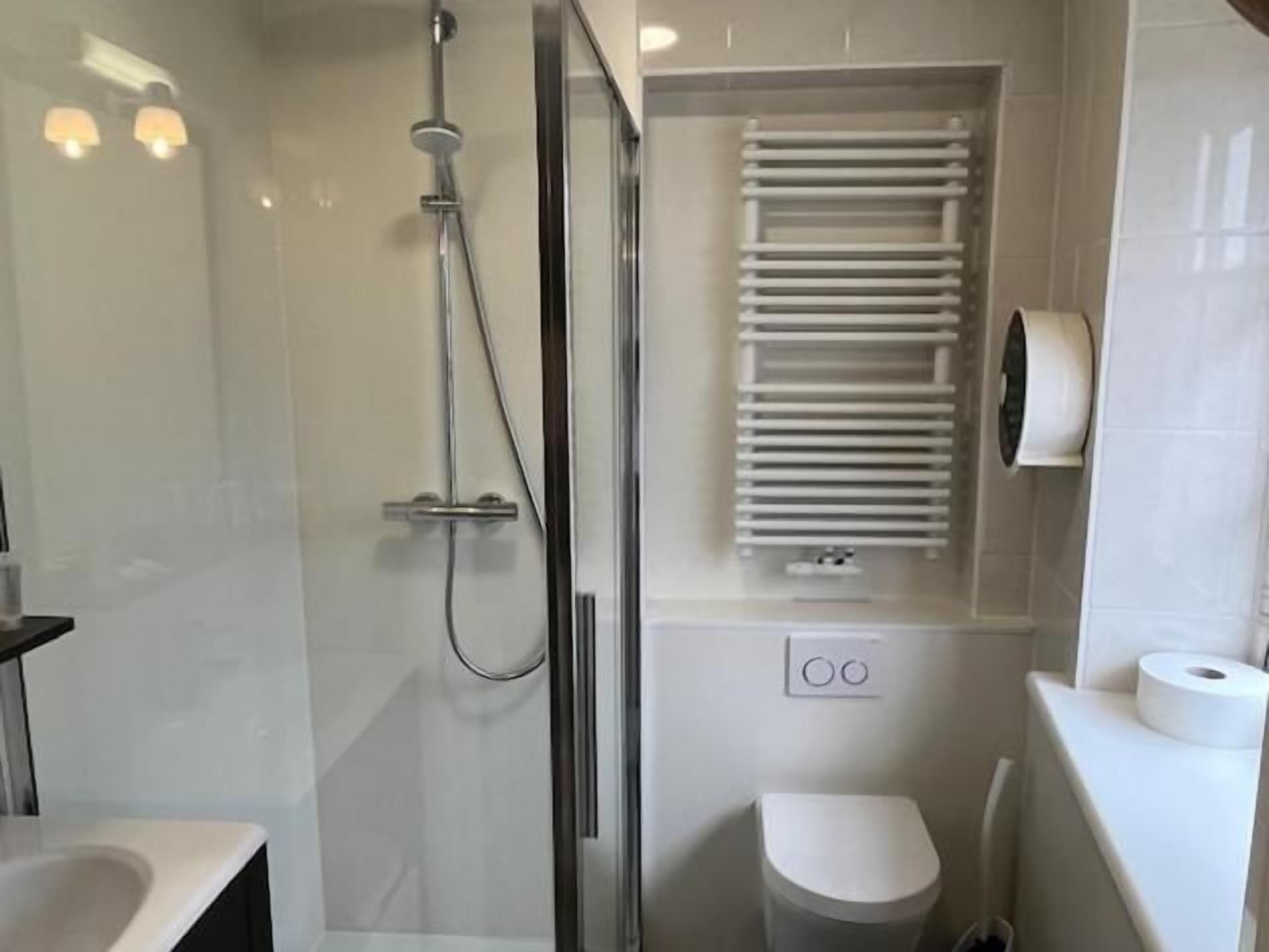 A modern bathroom with a glass-enclosed shower, a toilet, and a towel rack.