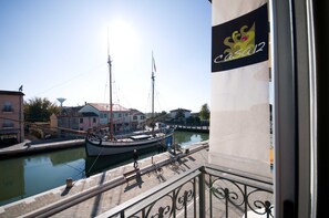A canal with boats, a person walking, and a building with a sign 'Casa12'. - CasaDodici (Cesenatico)